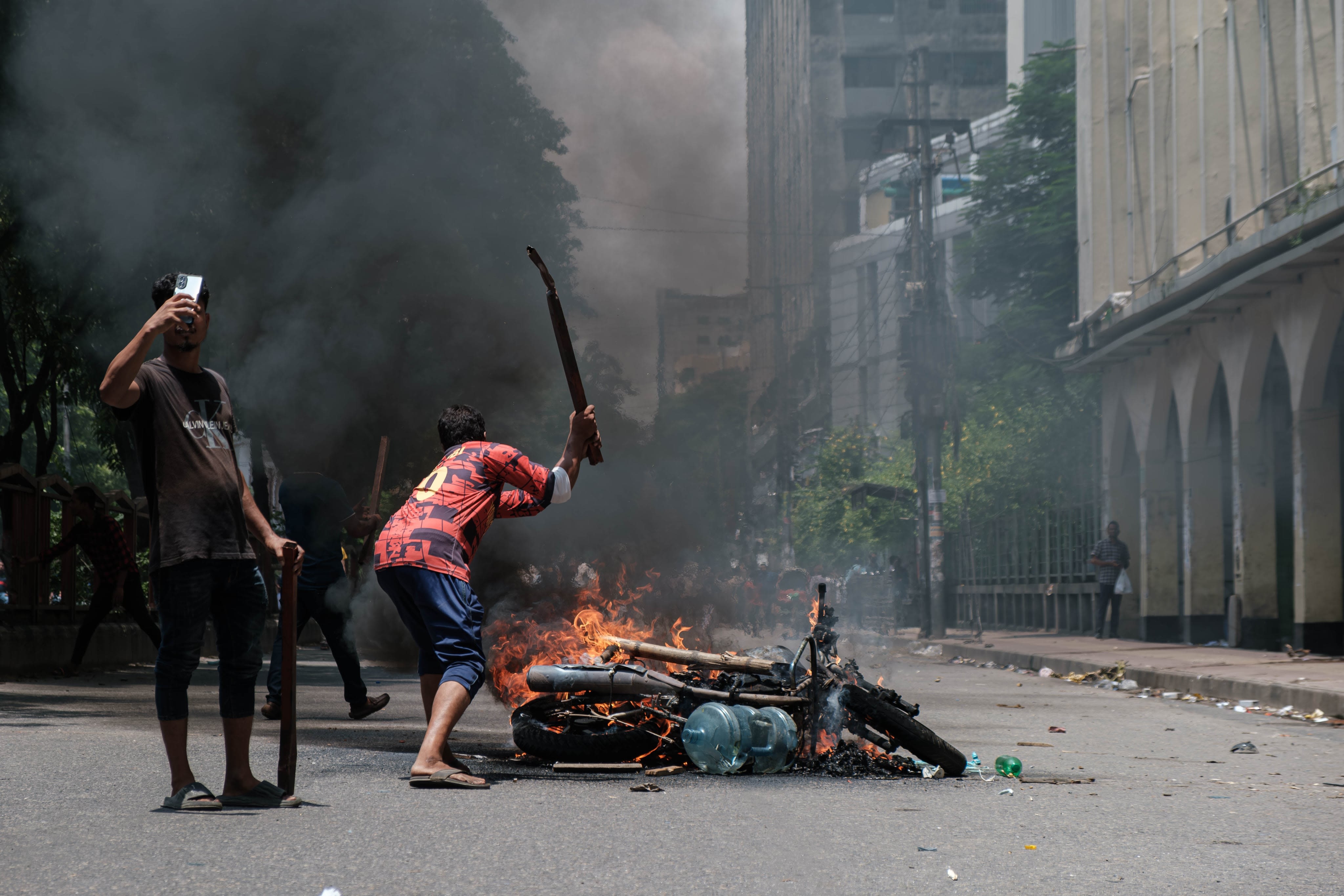 A protester breaking a burning police motorcycle due to the civil disobedience in Bangladesh to demand the government's resignation. Image Credits: Abul Hayat Rahadh.