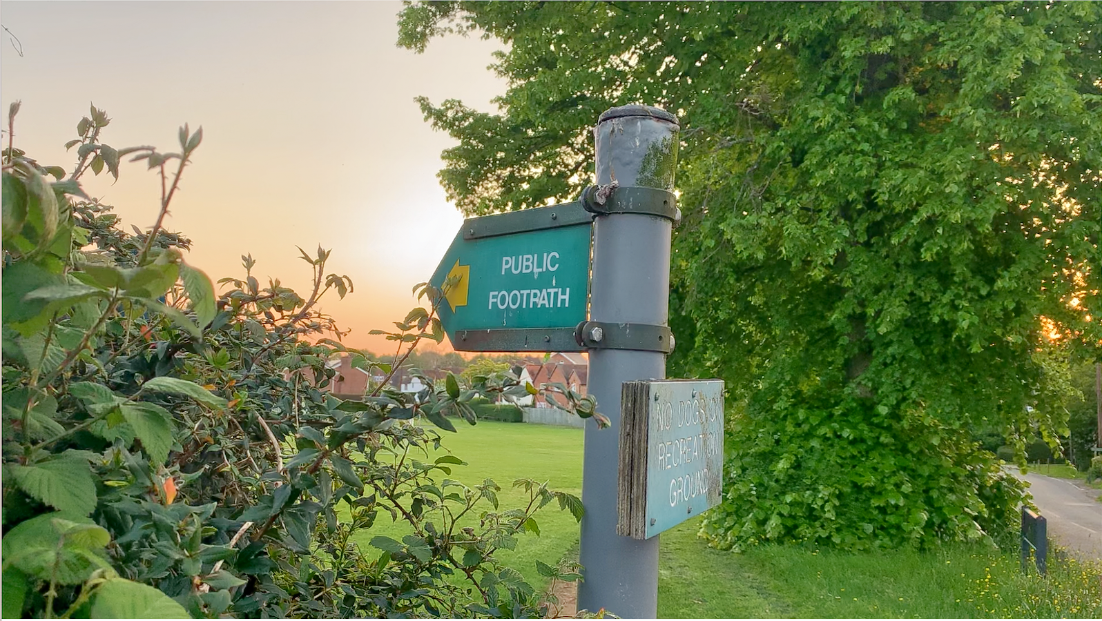 A public footpath sign with a sunset background